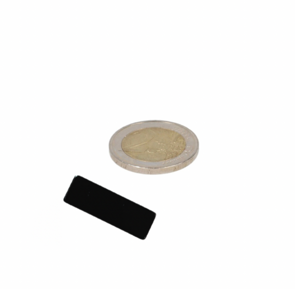 Black neodymium block magnet 30x10x2.5 mm n48 epoxy coated next to euro coin for industrial uses