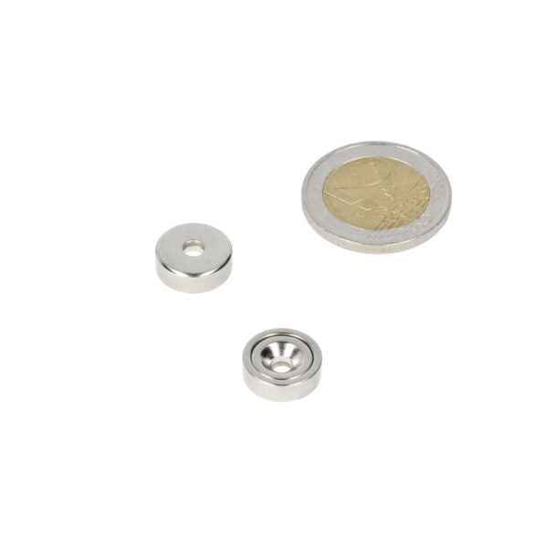 Silver-coloured neodymium pot magnet 13 x 4.5 mm with boron-zinc hole next to euro coin for magnetic force scale