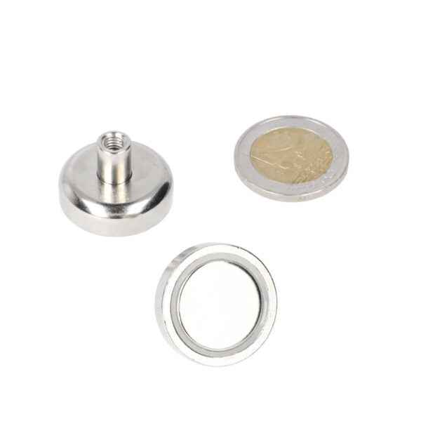 Silver-coloured pot magnet 25 x 7 mm with threaded bush m5 and ring next to a multi-purpose coin